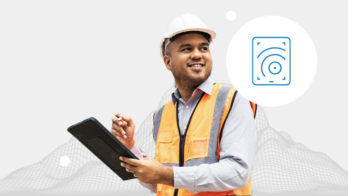 A person wearing a blue hard hat and safety glasses using a tablet overlaid on a wireframe of a mountain range