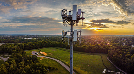 Mobilfunk-Mast vor einer Kleinstadt zur Sonnenuntergangszeit