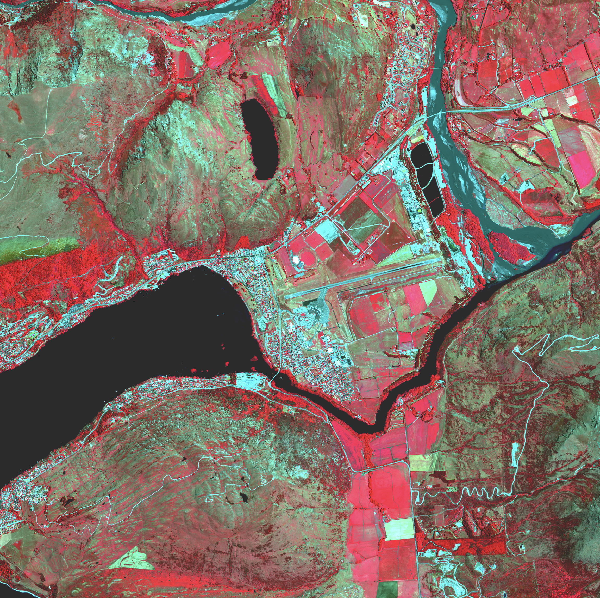 Die Karte einer Stadt an einem Fluss zeigt Brennpunkte und landwirtschaftliche Felder in Rottönen.
