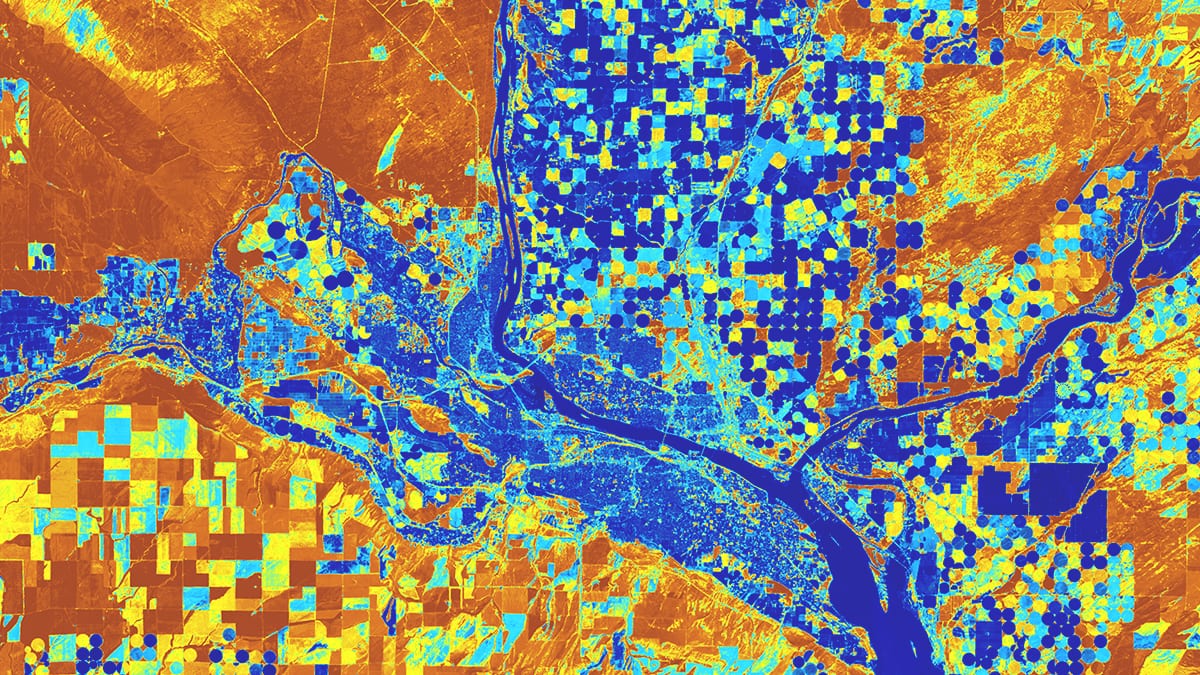 Ein Satellitenbild zeigt Grundstücke entlang eines Flusses mit quadratischen und kreisförmigen Feldern, die blau, orange und gelb markiert sind.
