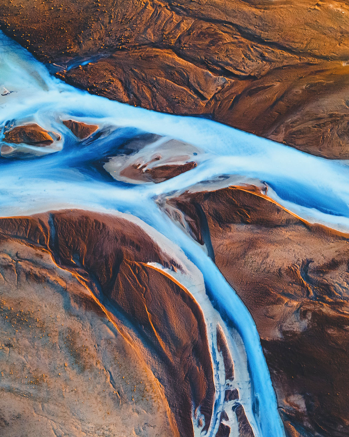 Ein Fluss fließt durch eine flache, verschneite Tundra-Landschaft mit einer Hochebene in der Ferne