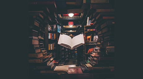 Ein aufgeschlagenes Buch, das in der Mitte eines kreisförmig angeordneten Bücherstapels schwebt